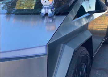 Pelúcia Asteroid Shiba com capacete de astronauta sobre uma Tesla Cybertruck